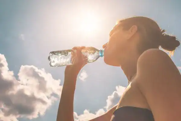 Image of woman drinking water to hydrate Basingstoke  after run.