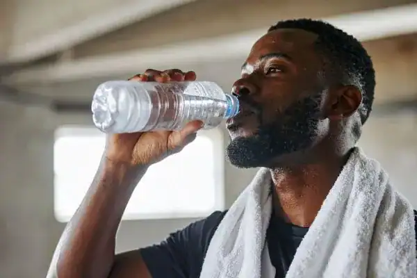 Image of man drinking water to improve hydration Basingstoke  after work out.